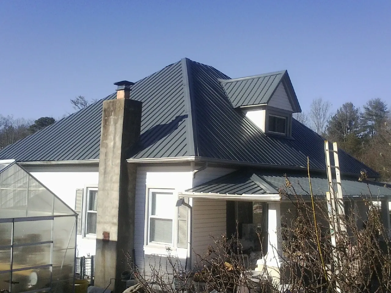 Dark blue standing seam metal roof on a white farmhouse with dormer — Slate & Tile Roof Repair by Roofing Brothers in Desert Hot Springs