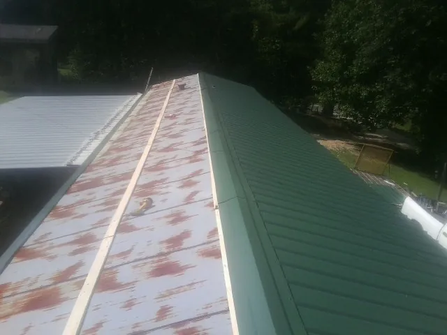 Old rusted panels beside newly installed green metal roofing — Wind Damage Roof Repair by Roofing Brothers in Desert Hot Springs