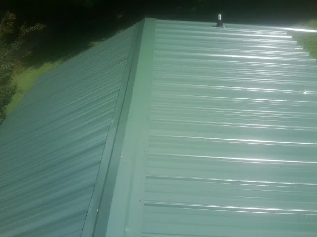 New green metal panels meeting at the ridge of a roof — Flat Roof Repair work by our crew in Desert Hot Springs