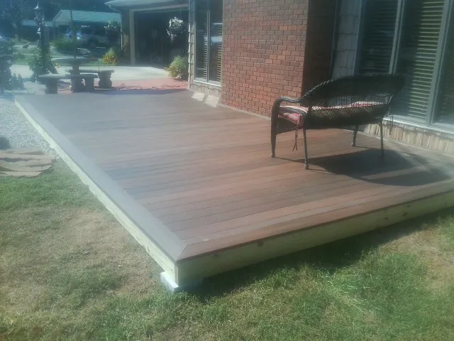 New wood deck and wicker chair beside a brick house in Desert Hot Springs