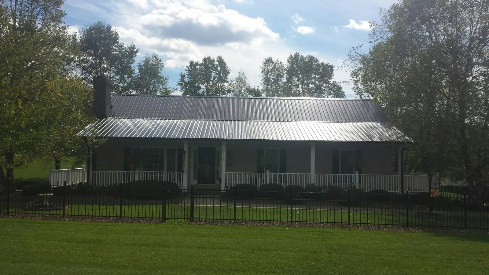 Gray metal roof on a brick ranch with a full width front porch — Gutter Guard Installation work by our crew in Desert Hot Springs
