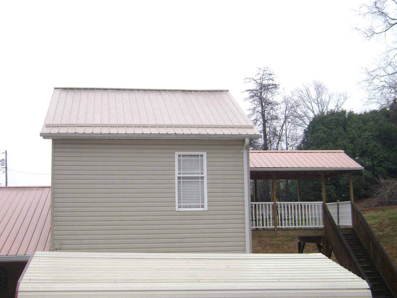 Tan metal roofs on a two story addition and attached porch, from a Roof Replacement job in Desert Hot Springs